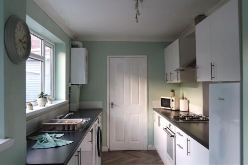 een keuken met een wastafel en een klok aan de muur bij Henderson Home Sleeps 3 with Allocated Parking in Pallion