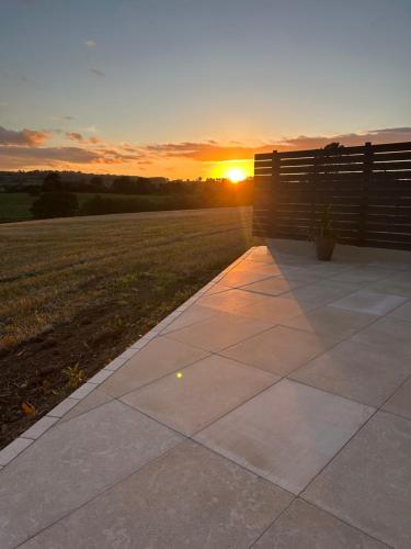 a sunset over a field with a bench and a sidewalk at Hollowdene in Gilford
