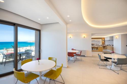 レティムノ・タウンにあるArchipelagos Hotelのテーブルと椅子があり、海が見えるカフェテリア