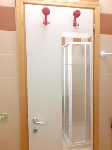 a glass shower door in a bathroom with two red handles at Appartamento Valfurva 15 in Santa Caterina Valfurva