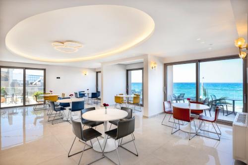 レティムノ・タウンにあるArchipelagos Hotelのテーブルと椅子と海のあるダイニングルーム