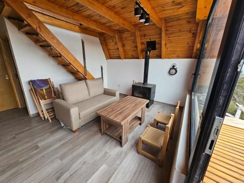 Una sala de estar con un sofá y una estufa de leña. en Complejo Bahia de los Sueños, Cabaña Maitenes, en Aluminé