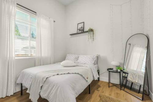 a white bedroom with a bed and a mirror at Amazing and Comfy Home With A Fire Place and Big Backyard in Orchards