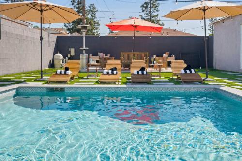 a swimming pool with chairs and umbrellas at Pool House Retreat near LAX, SoFi & Beach in Inglewood