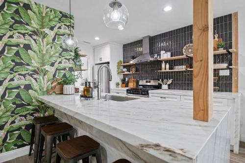 a kitchen with a large white counter and stools at Pool House Retreat near LAX, SoFi & Beach in Inglewood