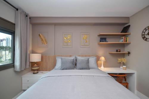 a bedroom with a large white bed and a window at Home Batel in Curitiba