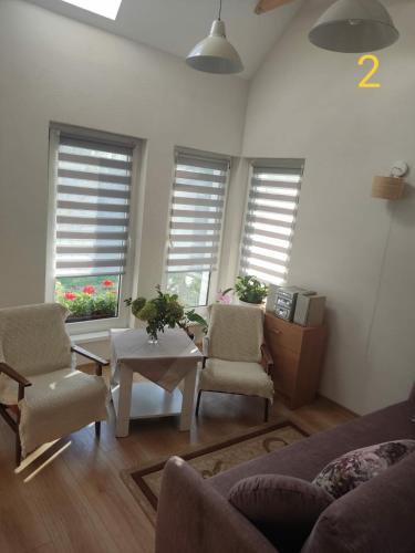 sala de estar con 2 sillas, mesa y 2 ventanas en Dom Zawiadowcy, en Budry