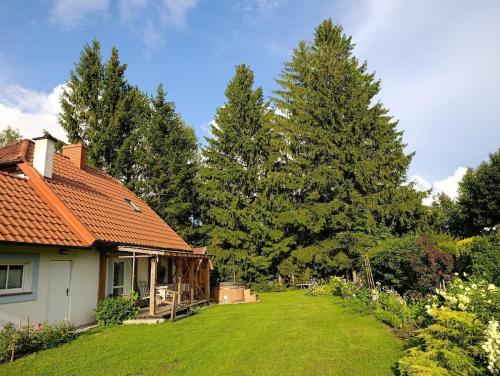 una casa con un patio con césped verde y árboles en Dom Zawiadowcy, en Budry