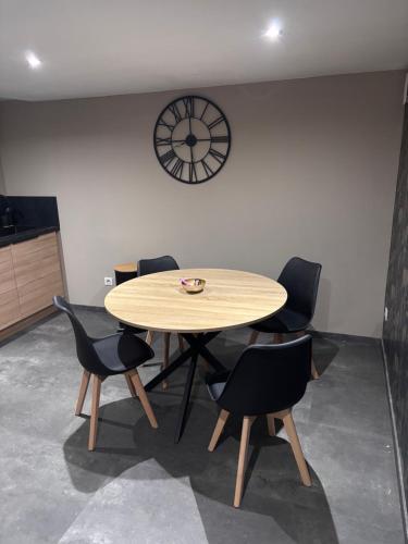 a table and chairs in a room with a clock on the wall at Aphrodite House in Guebwiller