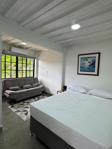 a bedroom with a large bed and a couch at Casa Bosque Vivo in Norcasia