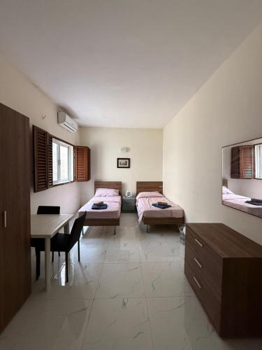 a room with two beds and a table in it at Fgura Spacious Apartments in Tal-Liedna