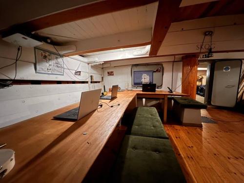 a room with a long wooden table with laptops on it at The Vega 1909 - Historic Wooden Ship in Amsterdam