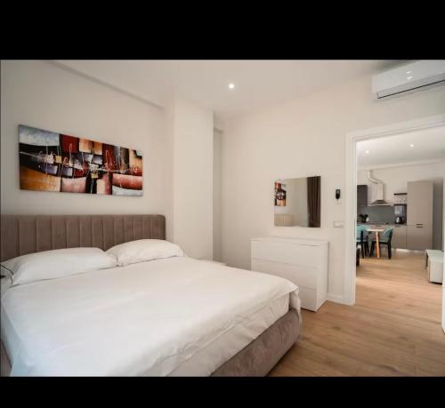a white bedroom with a bed and a dining room at Class Apartments in Tirana