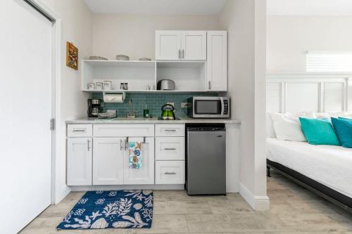 a kitchen with white cabinets and a microwave and a bed at The No Problem at Cottages in Sand Bluff
