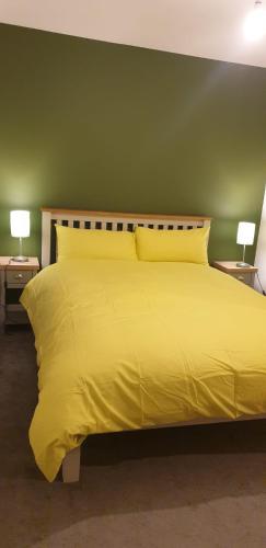a bedroom with a yellow bed with two lamps at Oatlands Oasis-FREE PARKING-2 Minutes from M74 in Glasgow