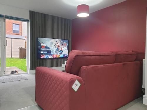 a living room with a red couch and a flat screen tv at Oatlands Oasis-FREE PARKING-2 Minutes from M74 in Glasgow