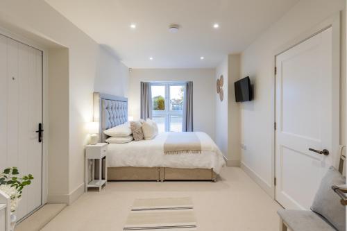 a white bedroom with a bed and a tv at Mudeford Beach Guest Room in Mudeford
