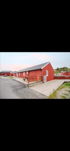 a red barn with a ramp next to a road at Stinebua in Vestvågøya