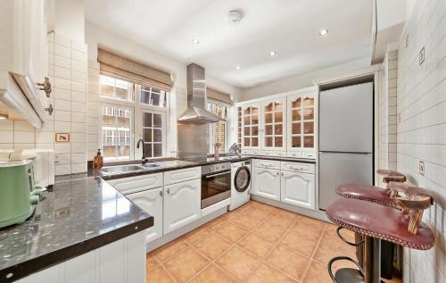 a kitchen with white cabinets and a sink and a dishwasher at ROYAL Apartment in HARRODS in London