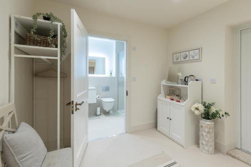 a white bathroom with a toilet and a doorway at Mudeford Beach Guest Room in Mudeford