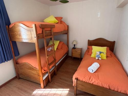 a bedroom with two bunk beds with orange sheets at Hermoso departamento en Viña del Mar in Viña del Mar