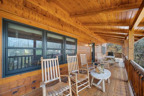 a porch with chairs and a table and windows at Sugars Cozy Cabin in Sugar Mountain