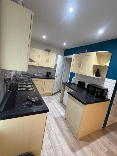a kitchen with white cabinets and black counter tops at Blaenavon Cosy Home in Blaenavon