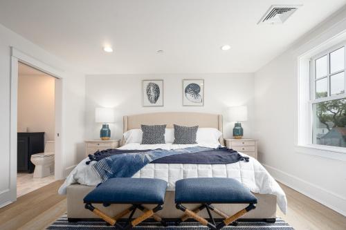 a white bedroom with a large bed with blue cushions at Thomas Sea Suites Penthouses in Plymouth
