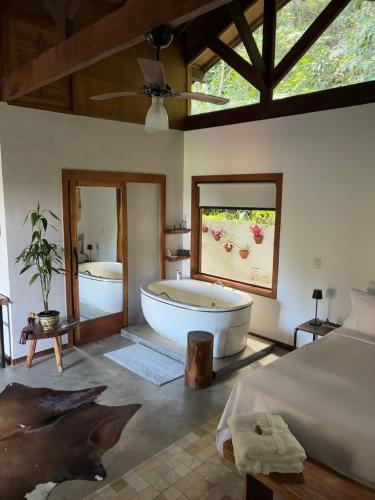 a large bathroom with a tub and a bed and a bedroom at Chalé Au Clair de Lune Terê in Teresópolis