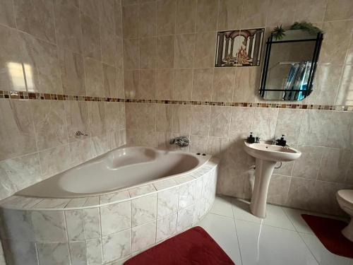 een badkamer met een bad en een wastafel bij 7th Dimension Guesthouse in Zeerust