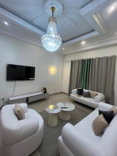 a living room with two white couches and a tv at Essentiel immo in Brazzaville