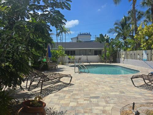 a swimming pool with chairs and a table at An Island Getaway at Palm Tree Villas in Holmes Beach