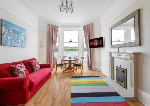a living room with a red couch and a table at Above The Bay in Port Bannatyne