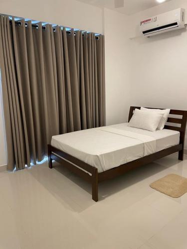 a bed sitting in a room with a curtain at Bright 3-Bed Flat with Balcony with Great Value in Sri Jayewardenepura Kotte