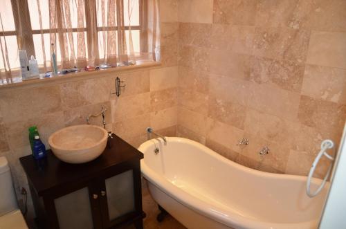 a bathroom with a tub and a bowl on a table at Critchley Hackle - Managers Cottage in Dullstroom