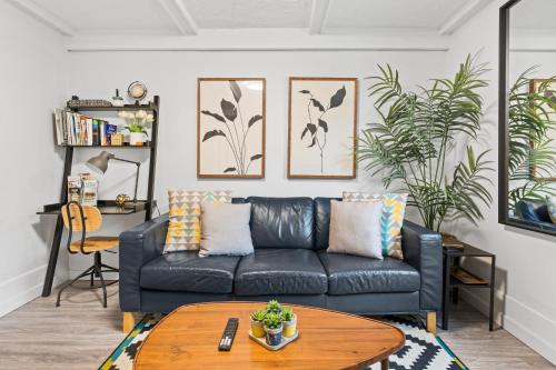 a living room with a black leather couch and a table at Heritage Home in Heart of City with free Parking in Vancouver