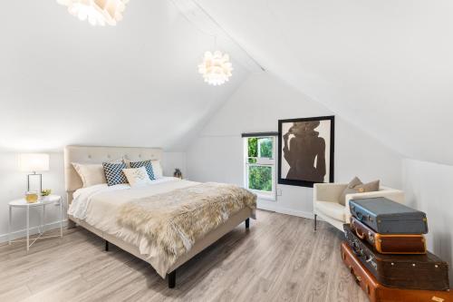 a white bedroom with a bed and a chair at Heritage Home in Heart of City with free Parking in Vancouver
