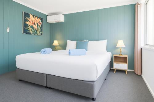 a bedroom with a large white bed with blue walls at Coast Motel Eden in Eden