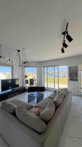 a large living room with a large couch and windows at Renata's Three bedrooms Penthouse with Sea view in Il-Gżira