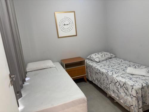 a small bedroom with two beds and a night stand at CasaAju - Sua nova opção de hospedagem em Aracaju, reformada e toda mobiliada, com tudo novinho, no capricho só para você in Aracaju