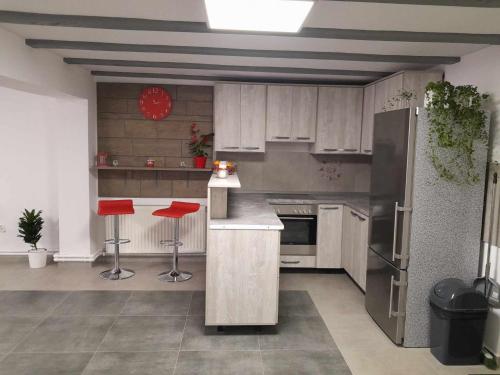 a kitchen with stainless steel appliances and red stools at Star Panzió in Harghita-Băi