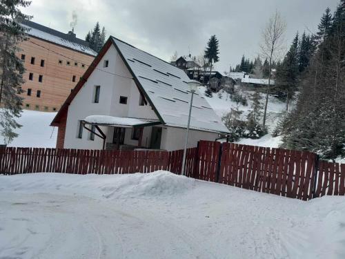 a house with a fence in the snow at Star Panzió in Harghita-Băi