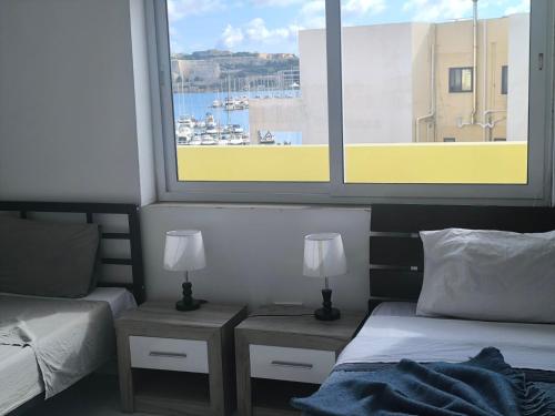 a bedroom with two beds and a large window at Renata's Three bedrooms Penthouse with Sea view in Il-Gżira