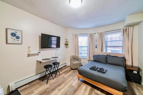 a living room with a bed and a desk at Cozy Studio near MassArt & Longwood, 3-Min Walk to T in Boston