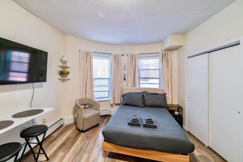 a bedroom with a bed and a desk and a tv at Cozy Studio near MassArt & Longwood, 3-Min Walk to T in Boston
