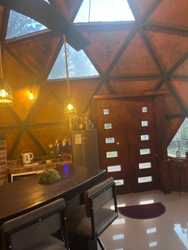 a kitchen with a wooden table in a room with windows at Tiny houses, domo en Temuco, Cumbres del Conunhuenu in Padre Las Casas