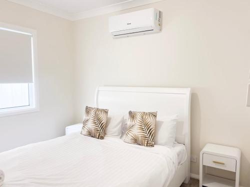 a white bedroom with a white bed with zebra pillows at Eliza's Escape 2 Wagga CBD in Wagga Wagga