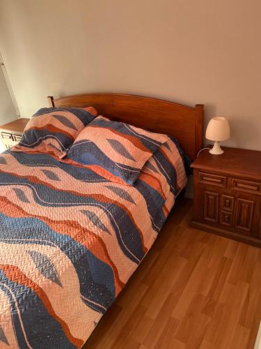 a bed with a comforter and a table with a lamp at Tiny houses, domo en Temuco, Cumbres del Conunhuenu in Padre Las Casas