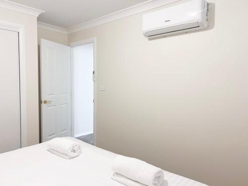a white room with a bed and a air conditioner at Eliza's Escape 2 Wagga CBD in Wagga Wagga