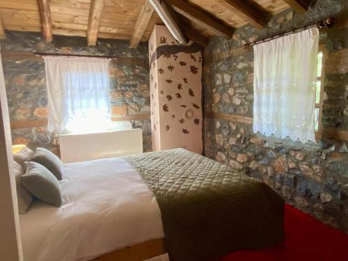 a bedroom with a bed and a stone wall at Elato Stone House in Panayítsa